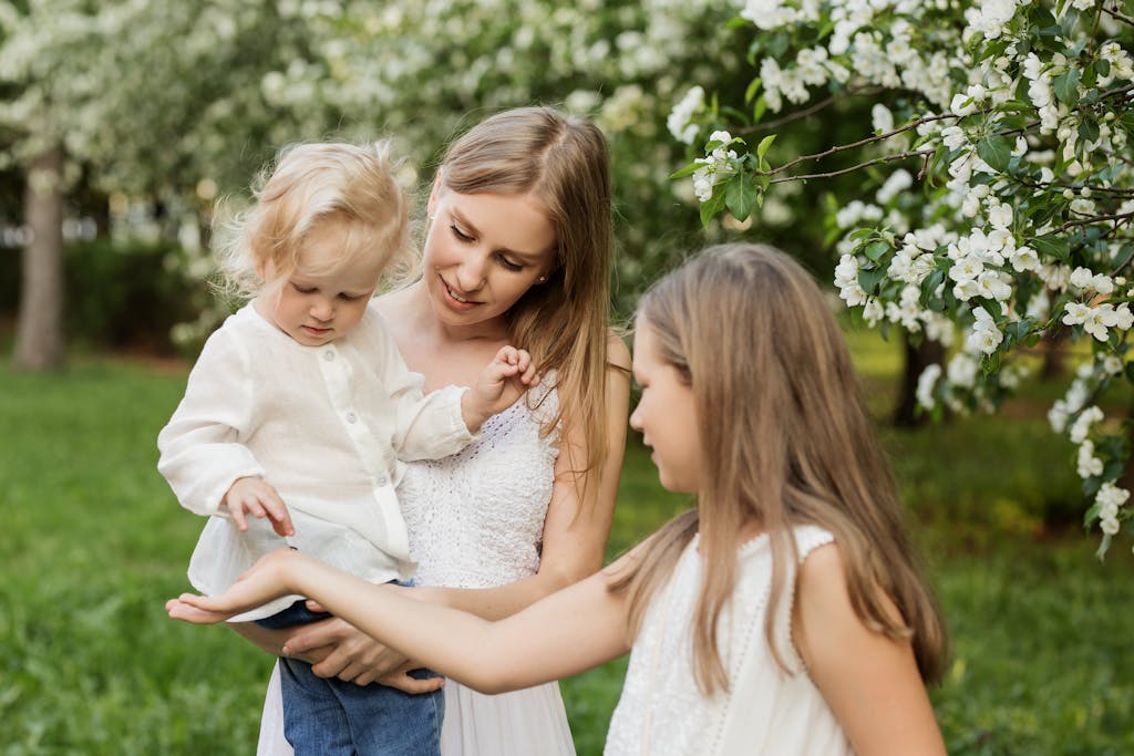 A mother and her children enjoy a spring day in a lush flowering garden, capturing family love.